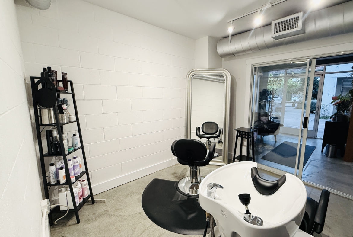 Bright salon interior with styling station, washbasin, and product shelf for rent.