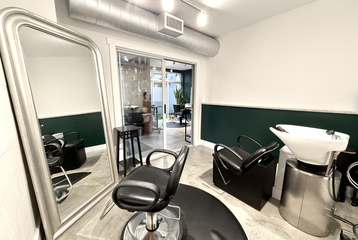 Elegant salon space featuring styling chairs, mirror, and hair wash station in a professional setting.