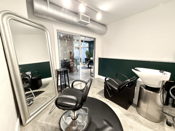 Elegant salon space featuring styling chairs, mirror, and hair wash station in a professional setting.