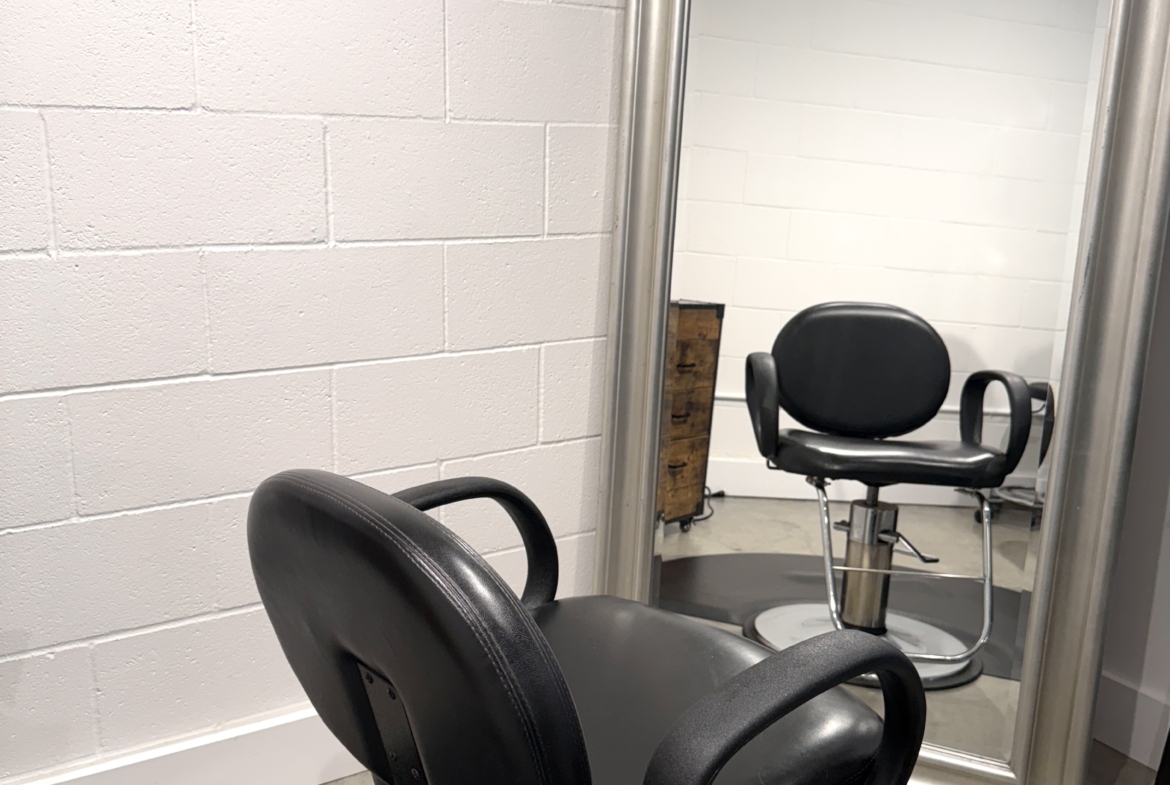Image of a salon styling chair in front of a large mirror for haircuts and styling.