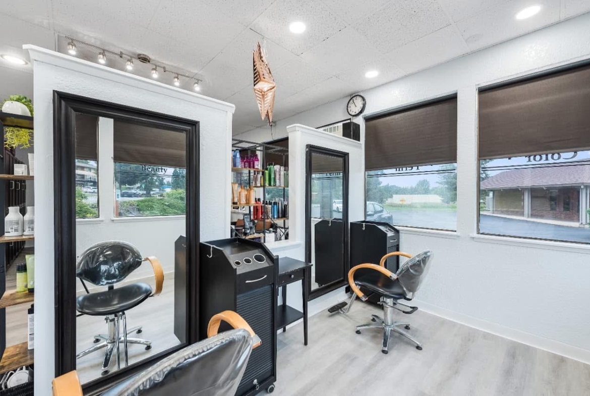 Modern salon rental station with styling chairs and product shelves.