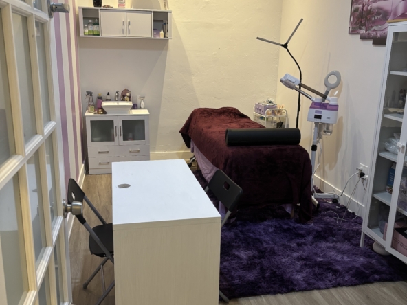 Brightly lit massage therapy room with cozy treatment bed and modern equipment.