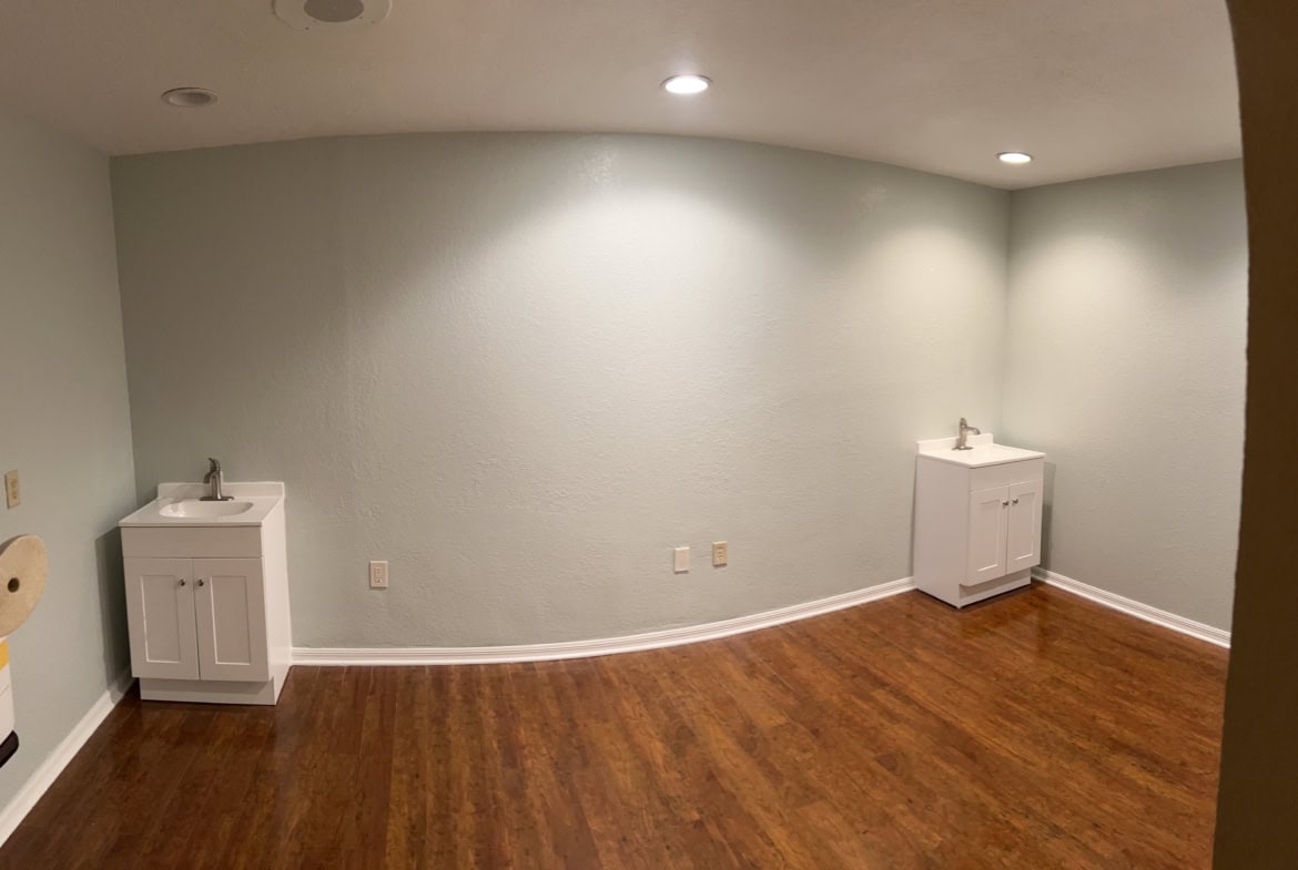 Clean salon or spa room with sinks for beauty services, hardwood floors, and neutral walls.