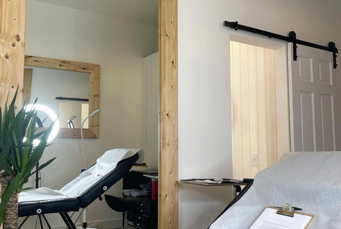 Bright salon space with treatment bed, mirror, and modern interior design for rent.