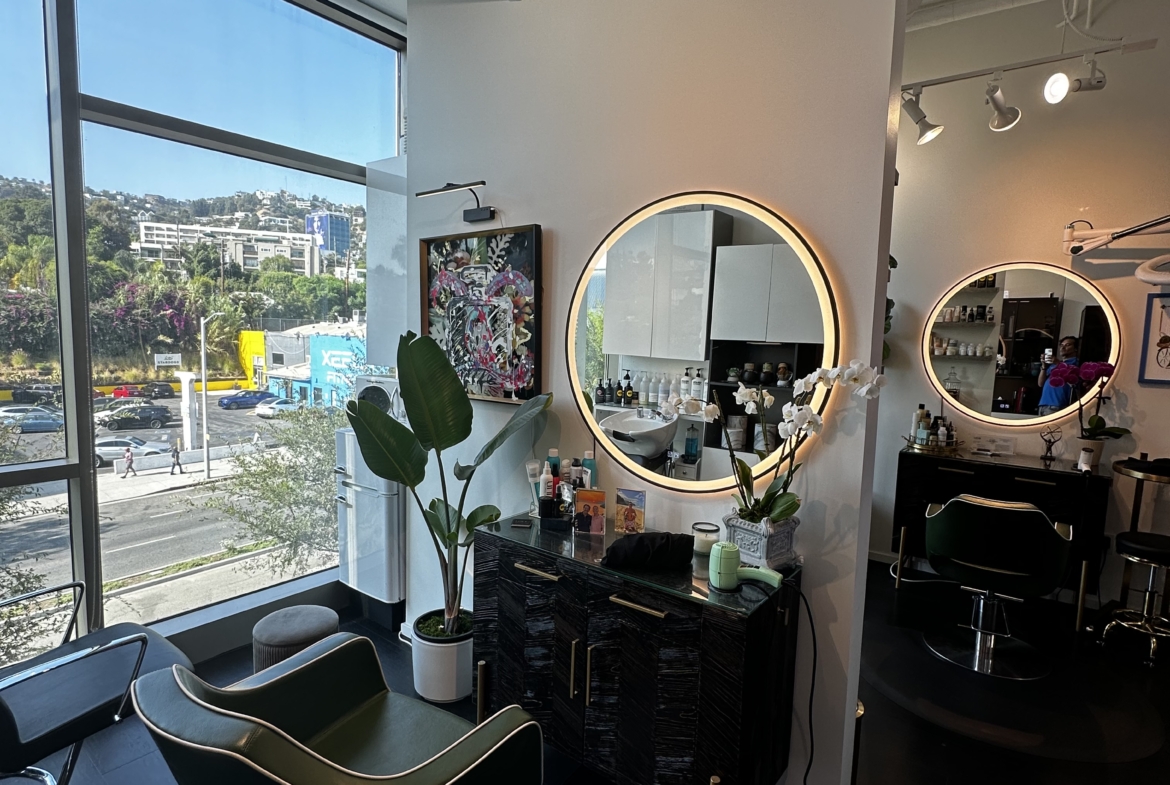 Bright, stylish salon with large windows, elegant mirrors, and contemporary decor.