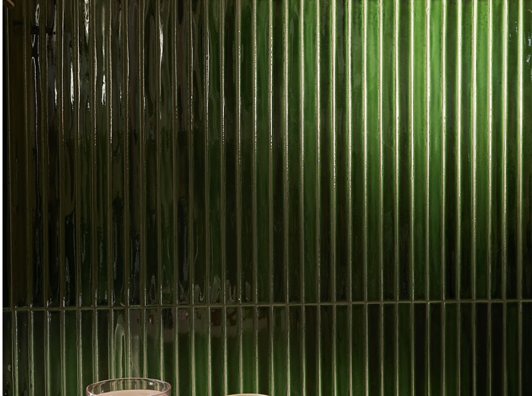 Bright and stylish salon interior featuring a cozy coffee table and vibrant green tiles.