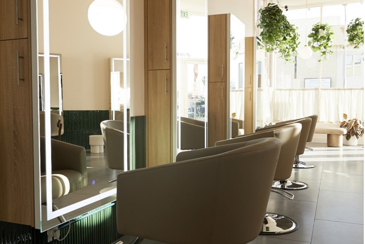 Bright, stylish salon interior with comfortable chairs, large mirrors, and natural lighting.