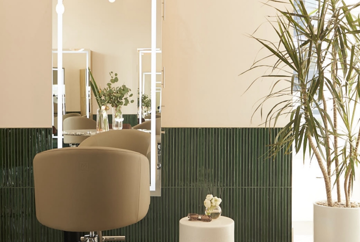 Bright salon space featuring a large mirror, comfortable chair, and stylish decor for rent.