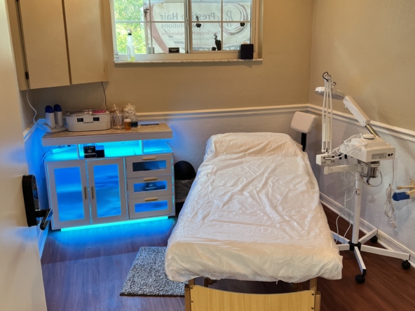 Comfortable beauty treatment room with massage bed and advanced skincare equipment.