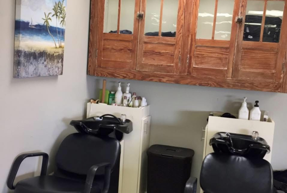 Comfortable black shampoo chairs with separate sinks in a professional salon setting.