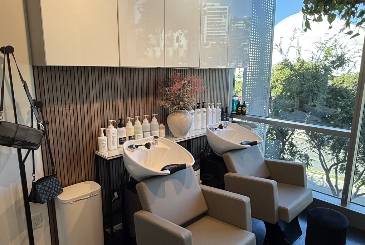 Hair salon shampoo station with comfortable chairs and product display.