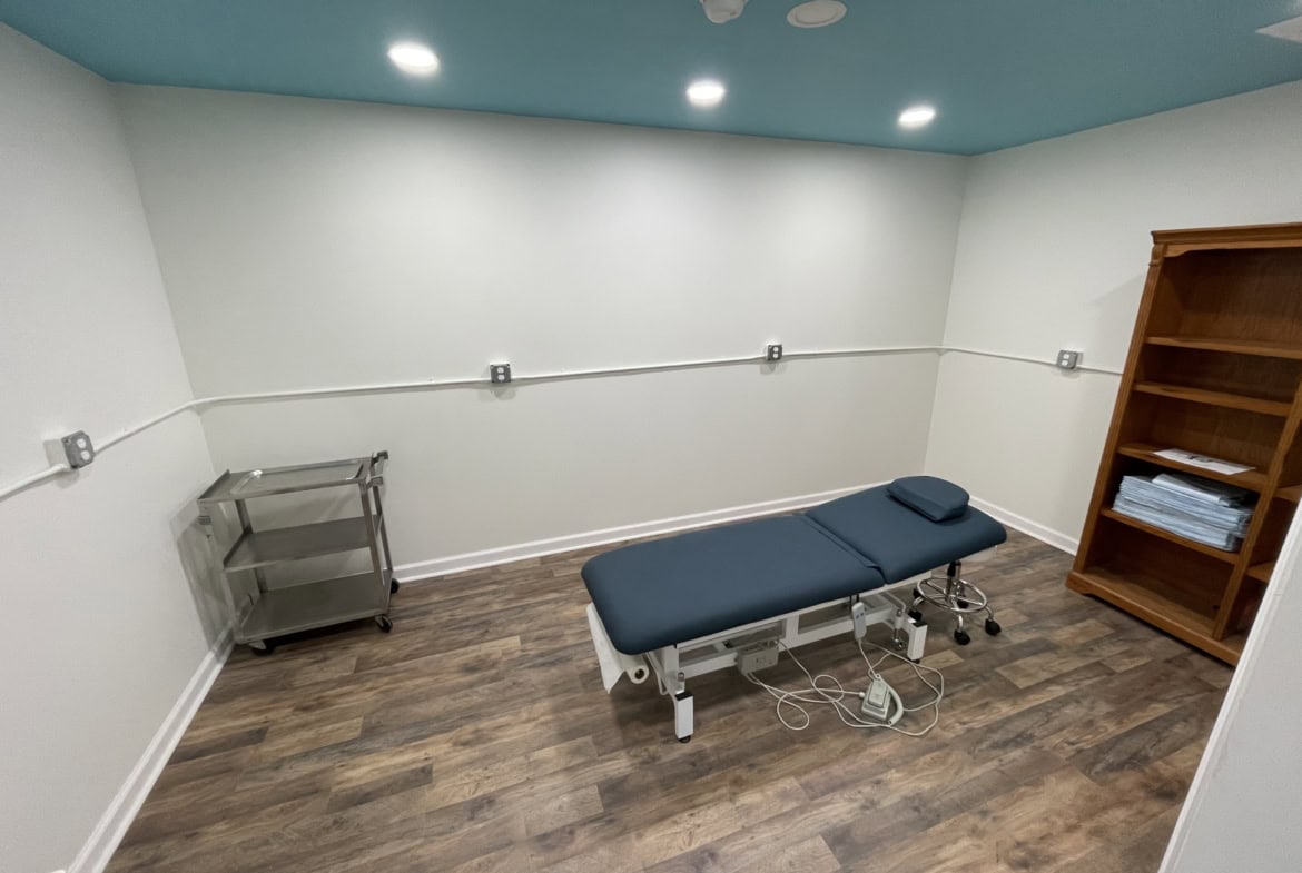 Comfortable massage therapy room with minimal decor and wooden flooring.