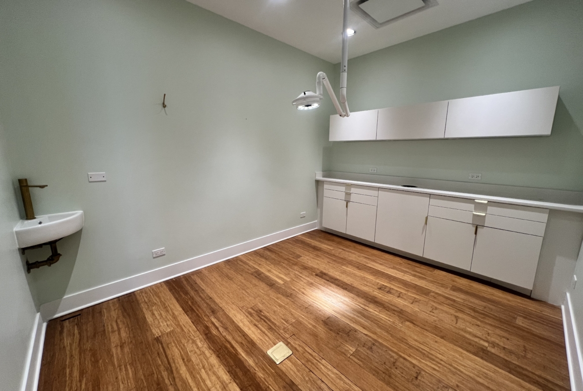 Bright salon room with white cabinetry and wooden floors, ideal for rent by beauty professionals.