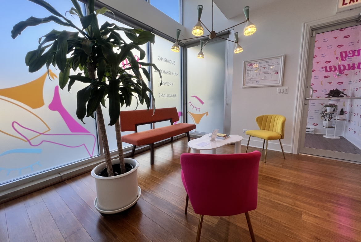 Bright salon waiting area with colorful chairs and large window light.