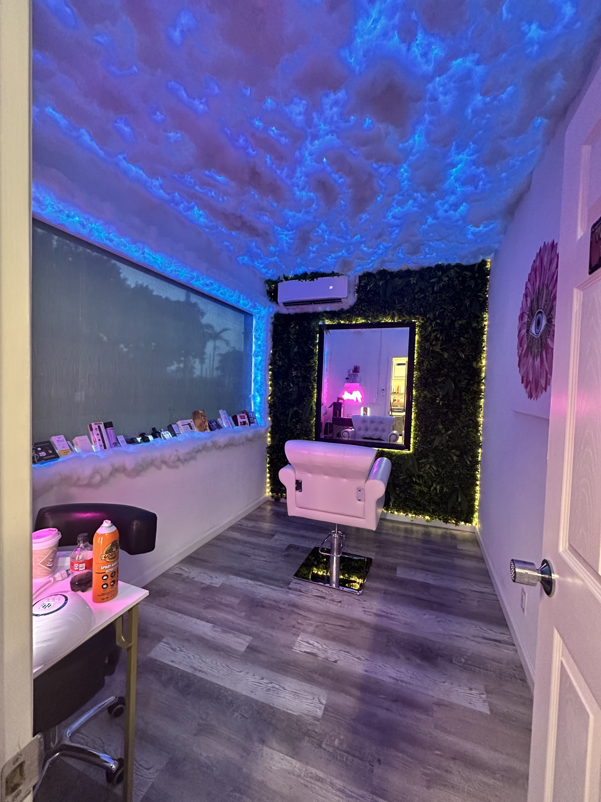 Stylish salon interior featuring cloud ceiling with blue LED lights, plush chair, and decorative wall for a relaxing beauty environment.