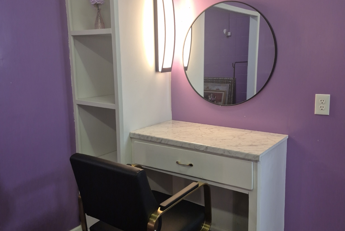 Vanity station with mirror, marble countertop, and styling chair in a professional salon.