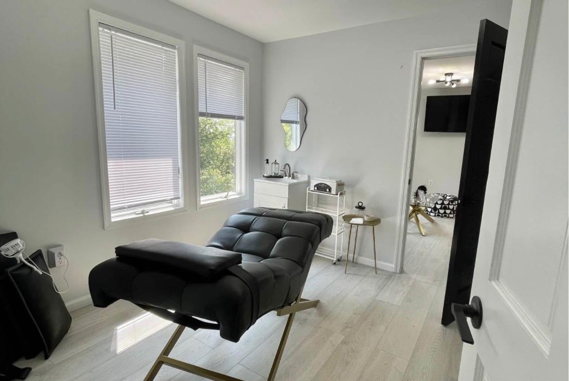 Bright salon room with massage bed and natural light fixtures.