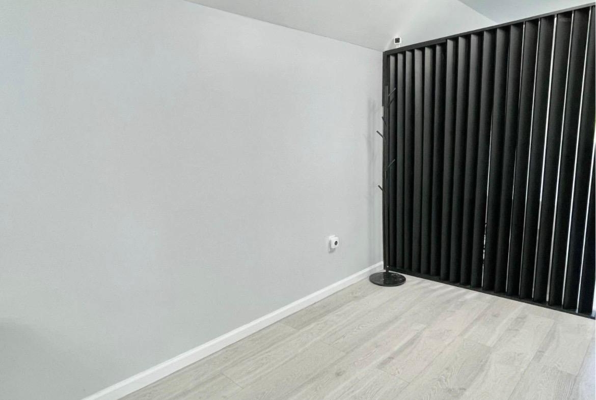 Clean, minimalist salon interior with light flooring and black room divider for studio rental.