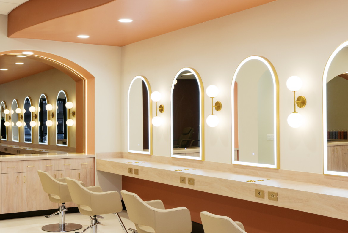 Elegant salon station with comfortable styling chairs and bright LED-lit mirrors for haircuts.