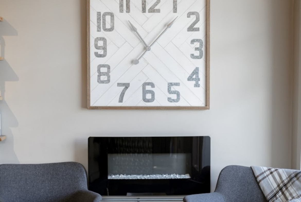 Bright, stylish salon interior featuring a large wall clock and cozy seating area for clients.