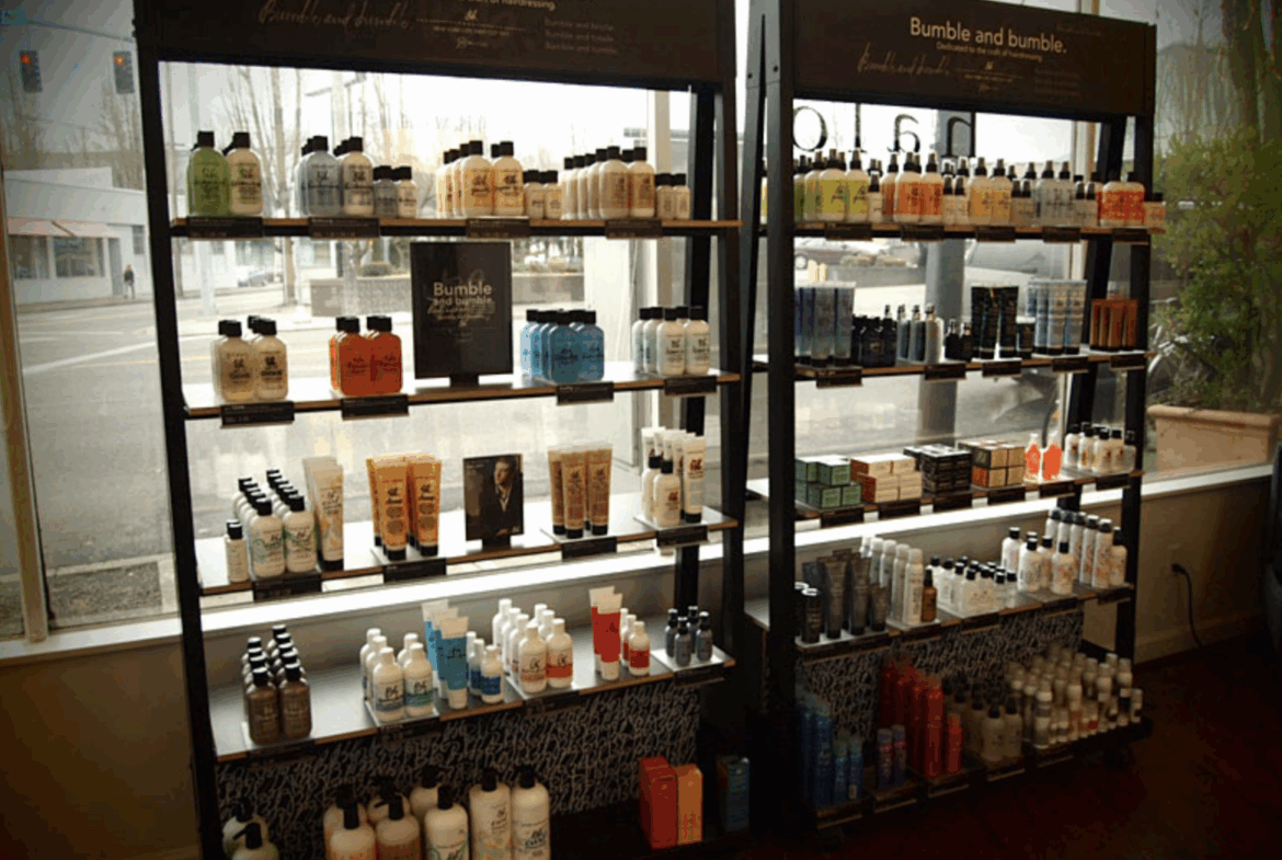 High-quality salon hair products on black shelving units near a window.