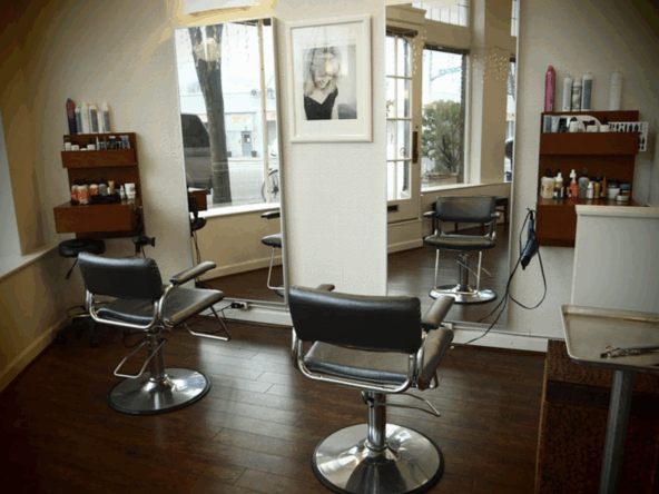Stylish salon beauty chairs with large mirrors and professional hair care products on shelves.