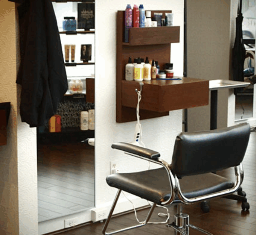 A sleek, modern salon chair with hair products and tools on a wooden wall-mounted shelf, ideal for professional beauty services.