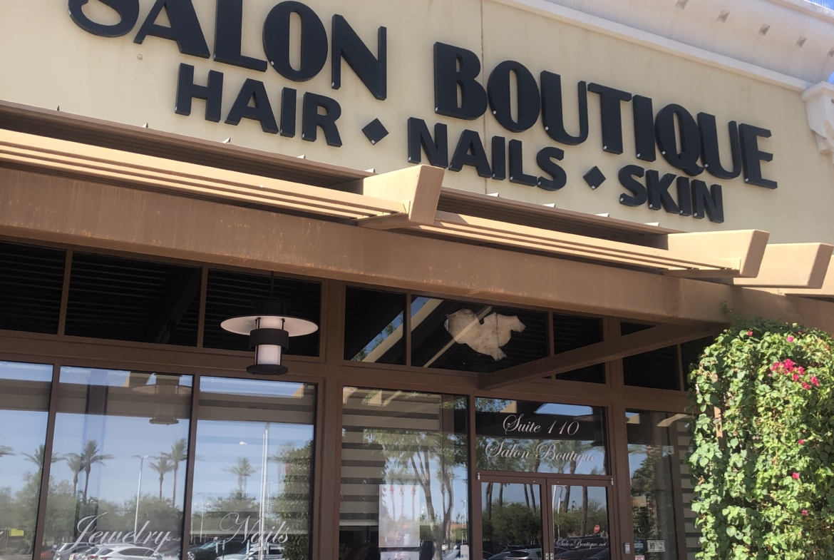 Bright storefront of a hair, nails, and skin salon with clear signage in a shopping plaza.