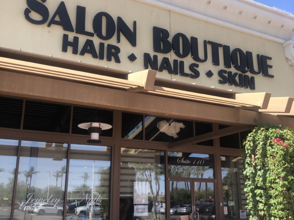 Bright storefront of a hair, nails, and skin salon with clear signage in a shopping plaza.