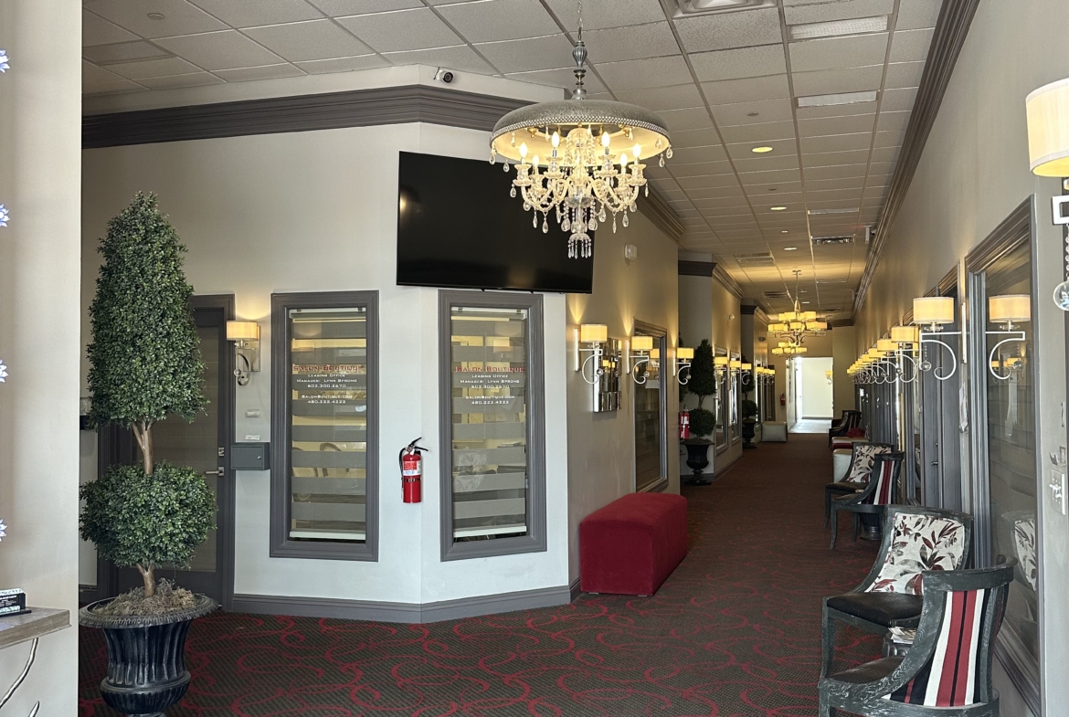 Chic salon lounge featuring chandelier, comfy chairs, and modern decor for client relaxation.