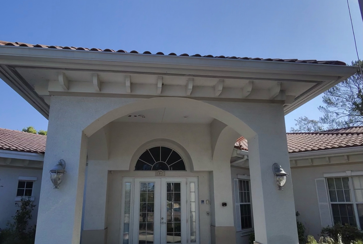 Bright image of a stylish salon storefront featuring a white facade, welcoming arched doorway, and decorative outdoor lighting.