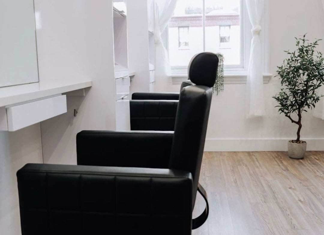 Relaxing salon styling station with comfortable black chairs and natural light.