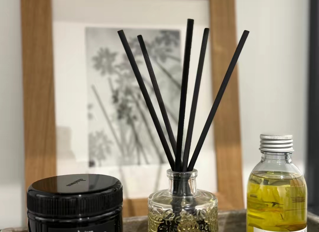 Stylish diffuser and hair products on a bathroom shelf.