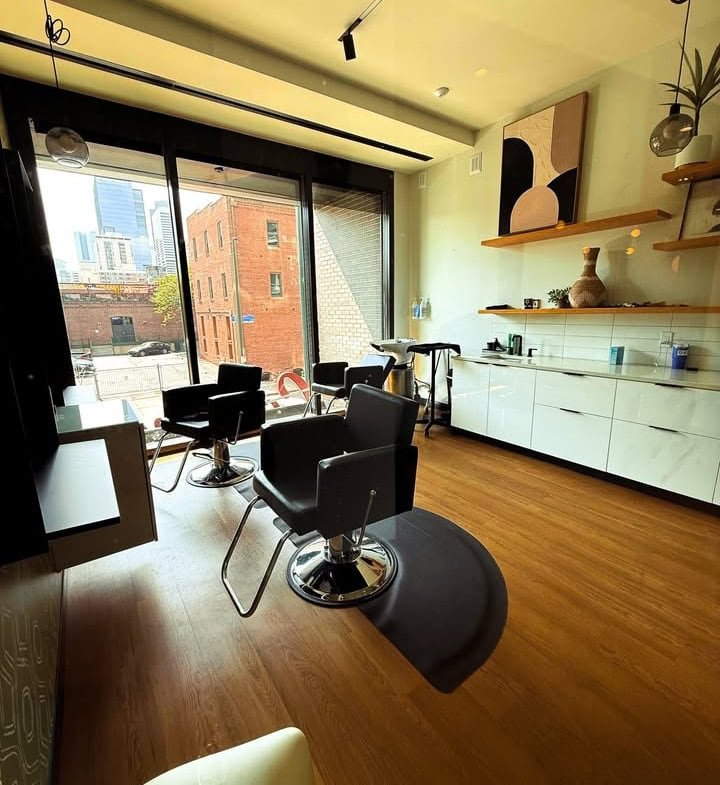 Bright modern salon interior with chairs and large windows for hair styling and beauty services.