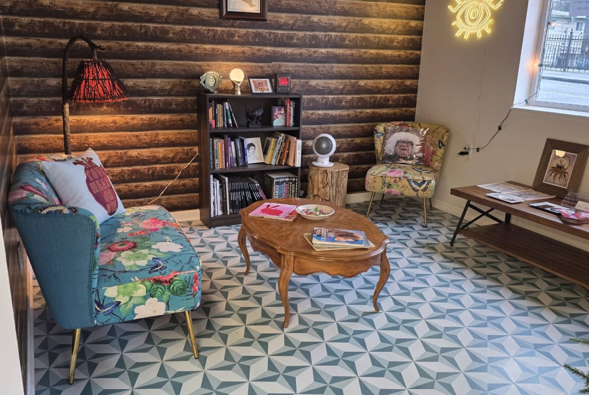 Bright salon lounge featuring colorful furniture, patterned floor tiles, cozy seating, and decorative lighting.