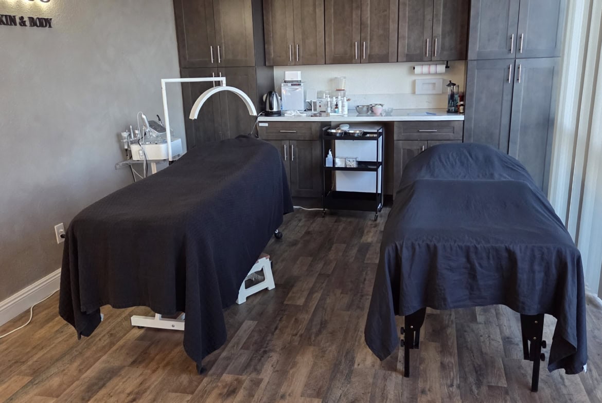 Professional massage therapy room with two treatment tables, relaxing environment, modern cabinetry, and equipment.