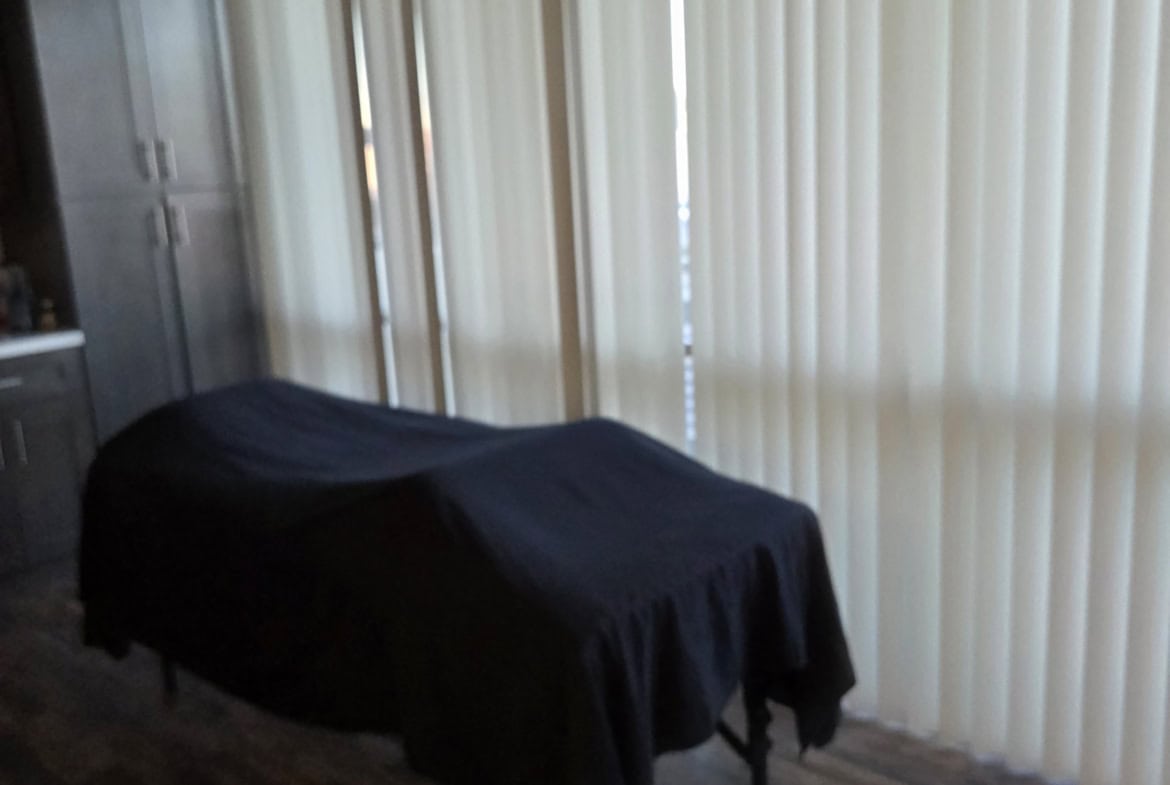 Relaxing massage room with massage table and vertical blinds in salon or spa setting.