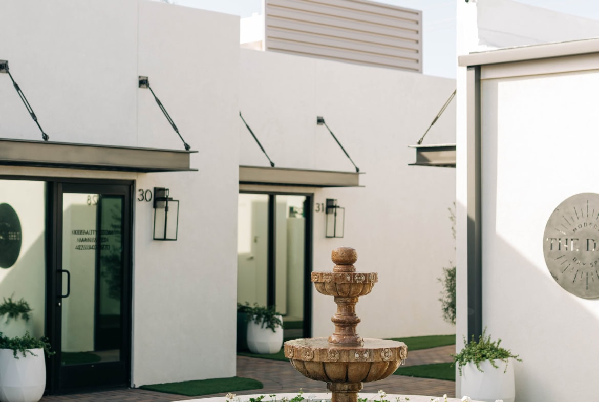 Elegant salon storefront with modern architecture, outdoor fountain, and stylish decor, perfect for salon rental spaces.