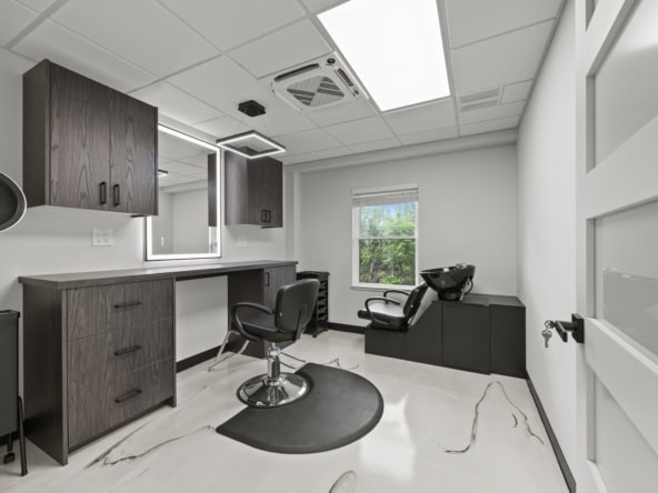 Bright modern salon station with styling chair, mirror, and hair washing station, ideal for salon rent.