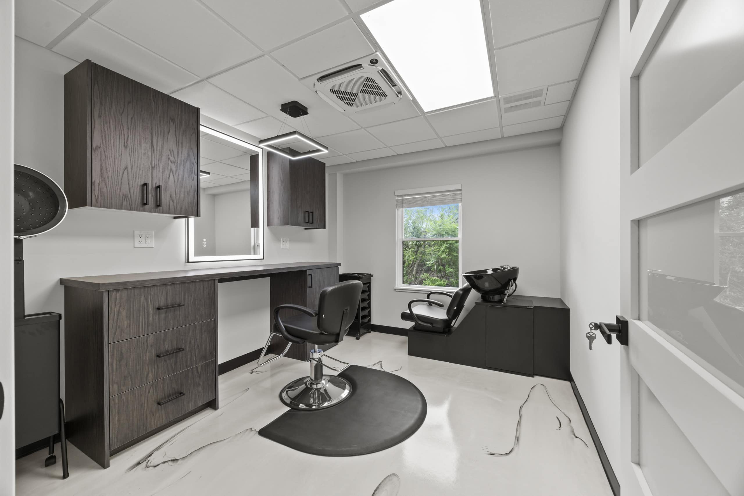 Bright modern salon station with styling chair, mirror, and hair washing station, ideal for salon rent.