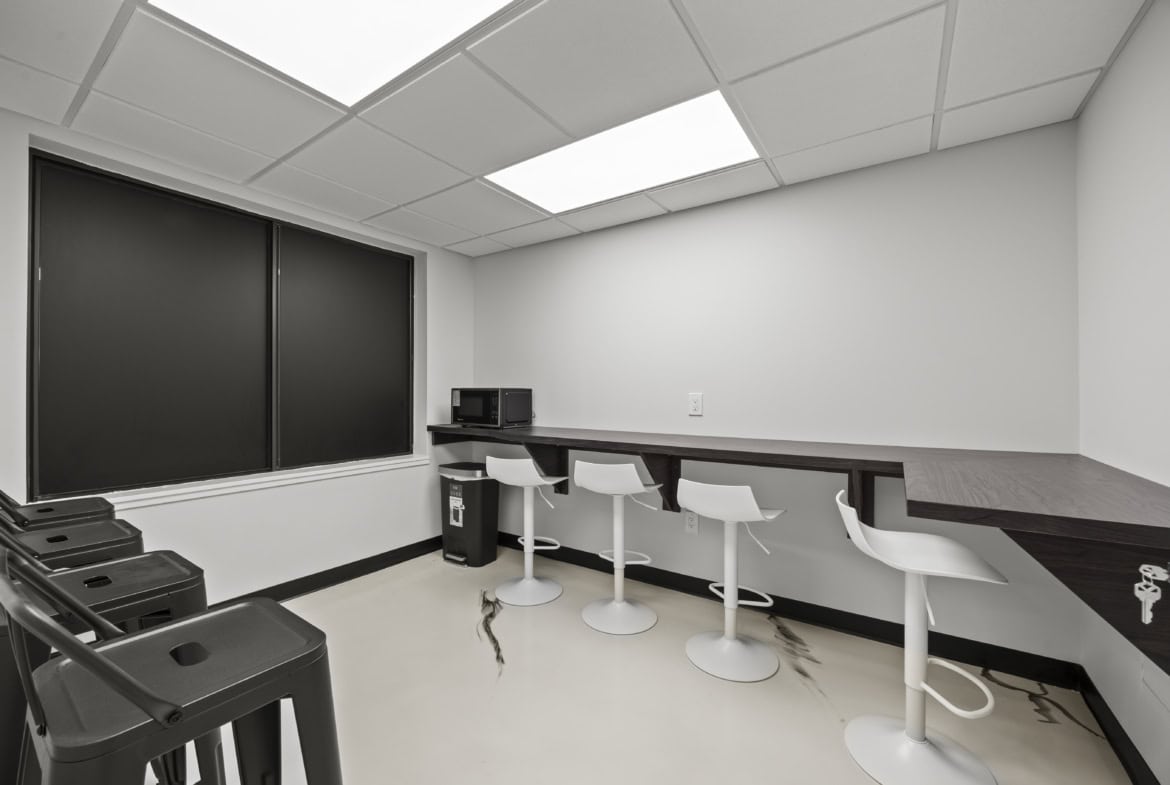 Clean empty break room with high top counter and barstools, modern office kitchen, minimal decor, for salon or business workspace.