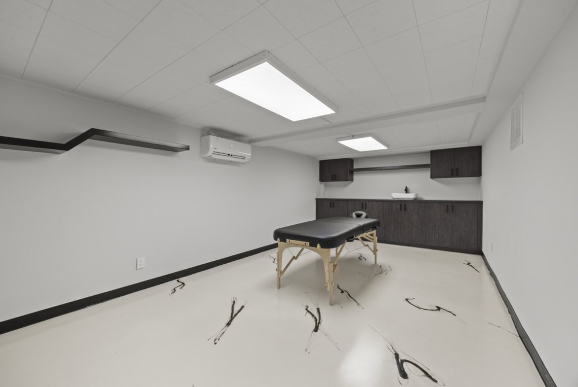 Bright, minimalist massage therapy room with massage table and modern cabinetry for relaxing treatments.