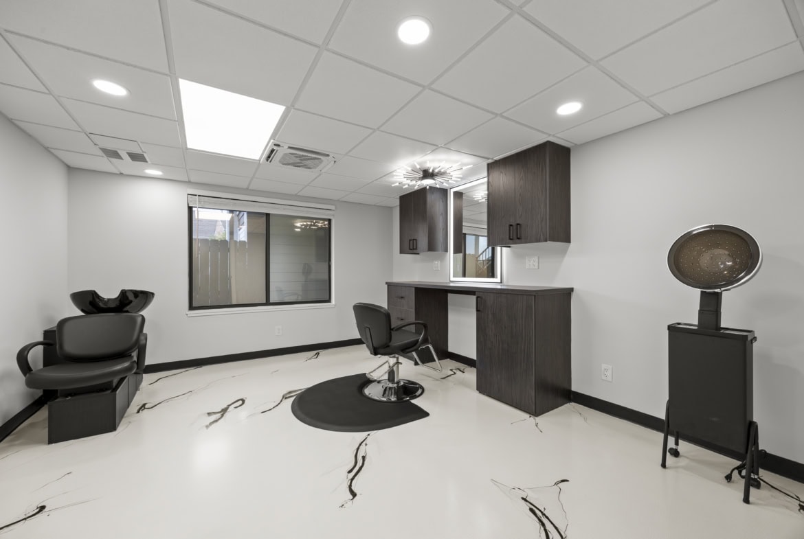 Bright, modern salon hair station with styling chair, wash basin, and storage cabinets for rent.