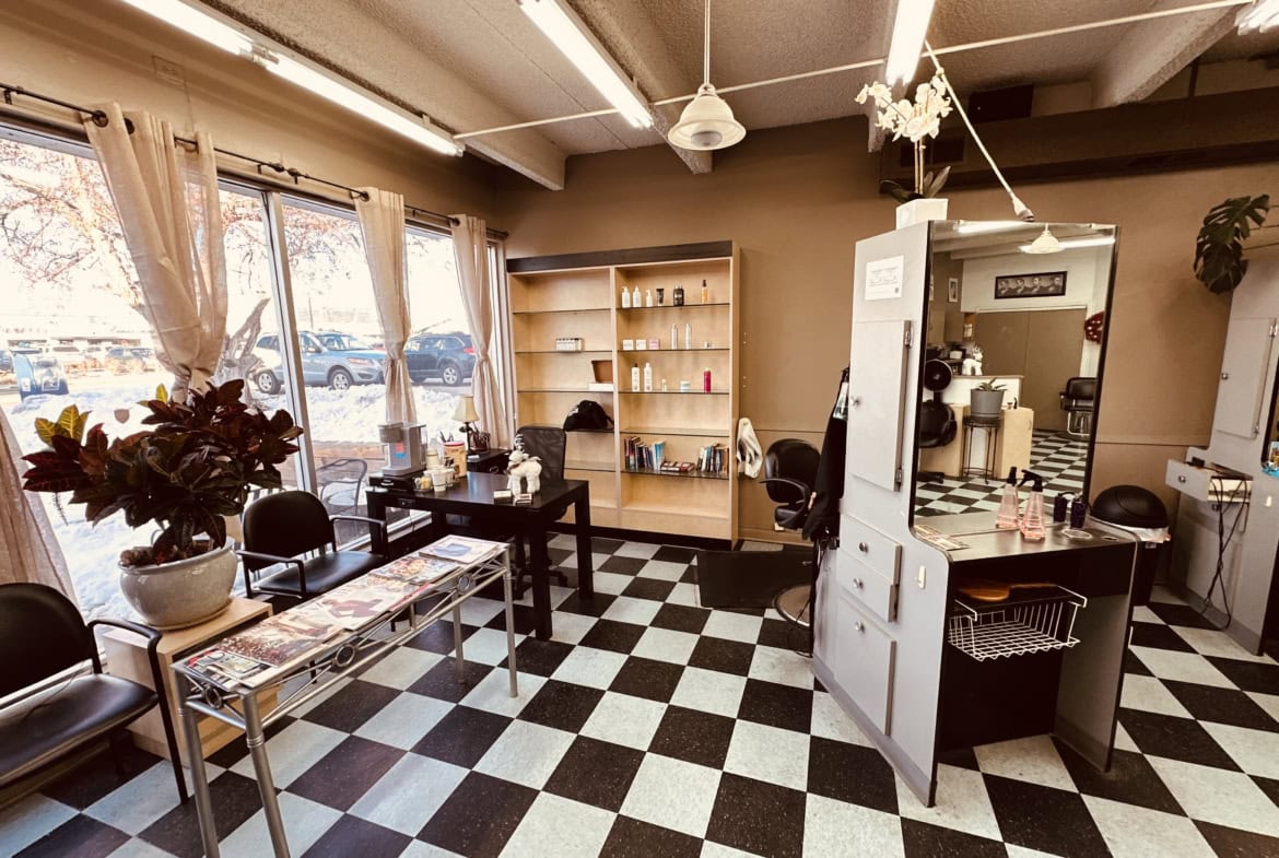 Bright salon interior with natural light, stylish checkered flooring, and organized styling stations.