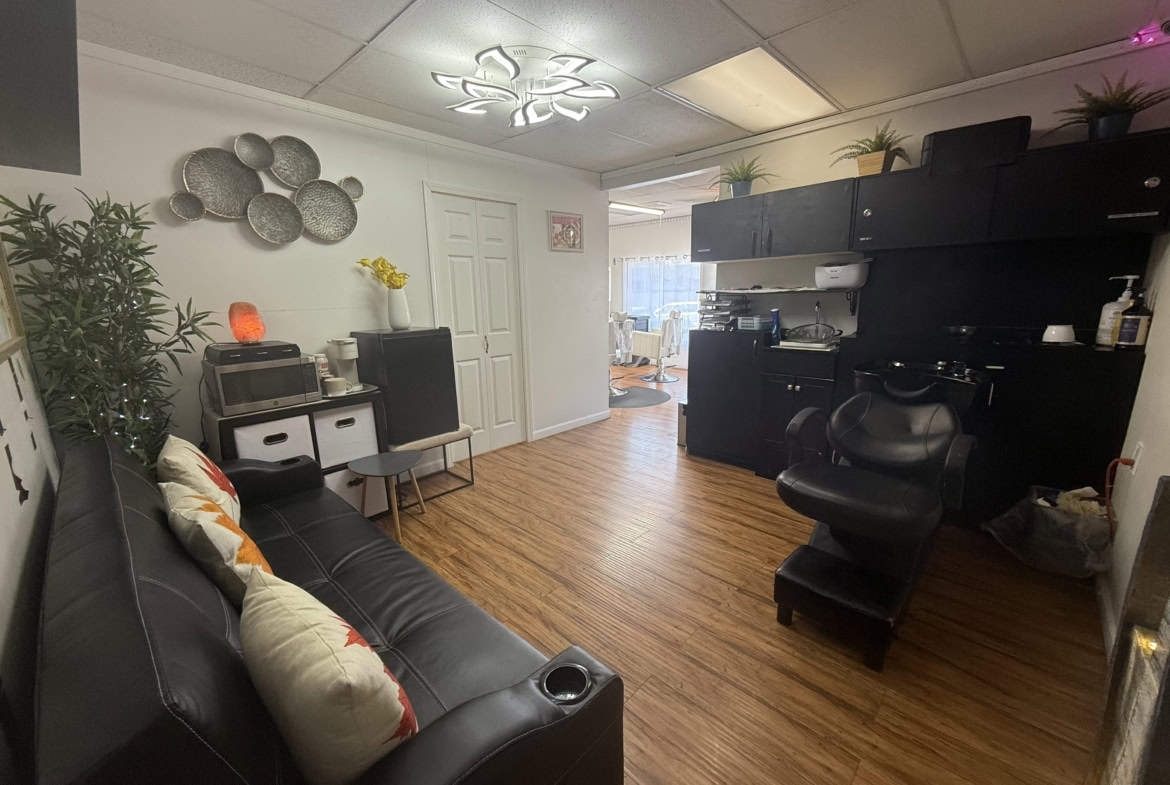 Cozy salon or studio space with black furniture, plants, and a welcoming atmosphere for clients.