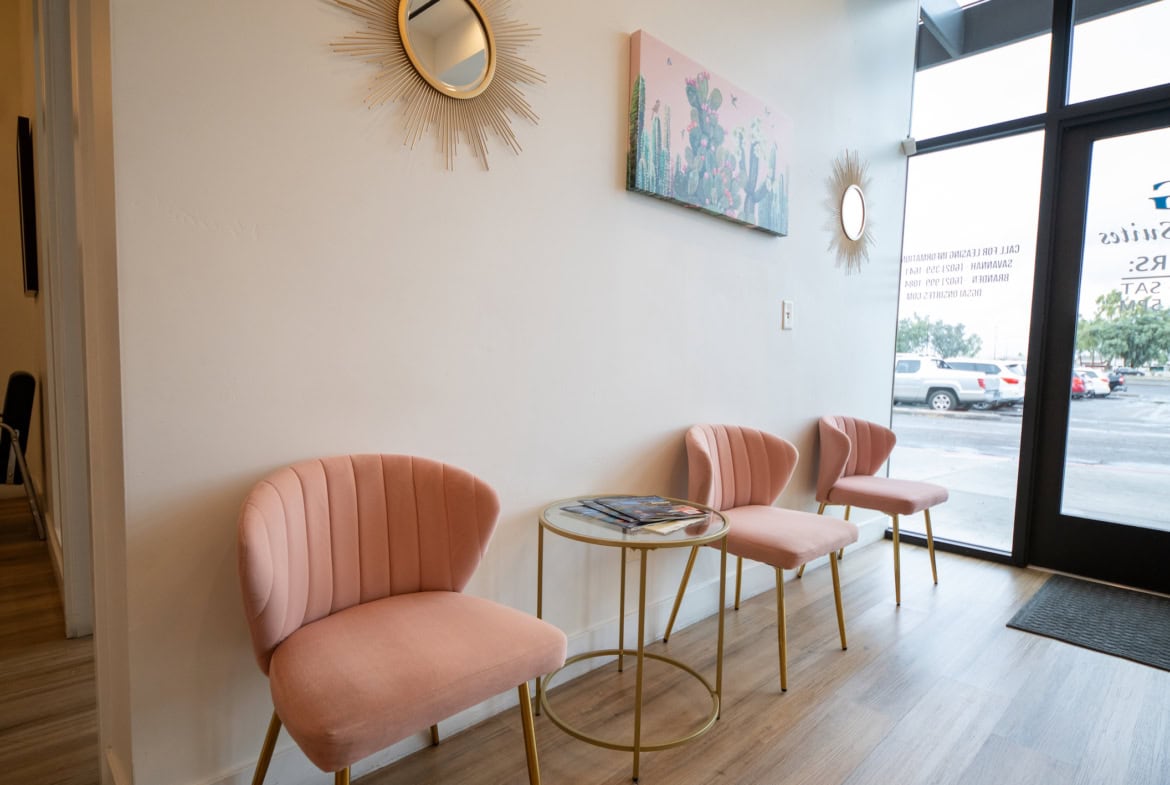 Bright salon lobby featuring pink upholstered seating and modern wall decor.