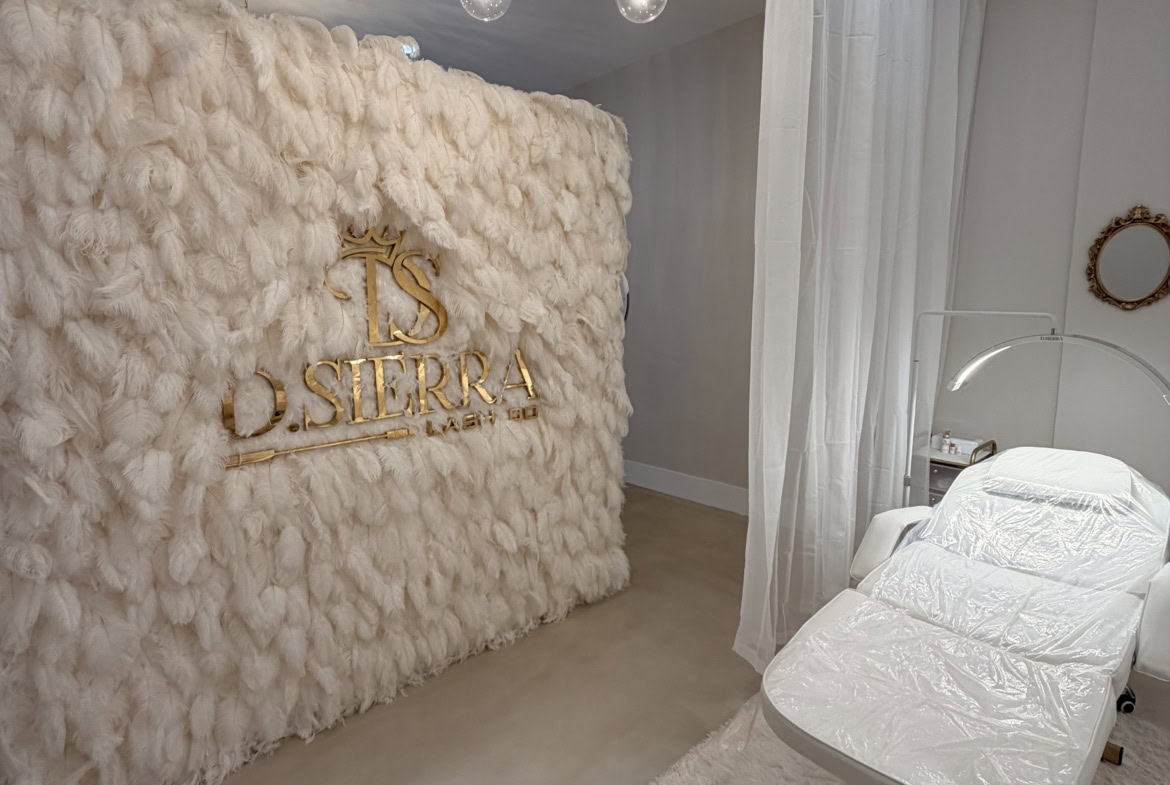 Elegant salon interior with plush white decor, stylish lighting, and a comfortable treatment chair.