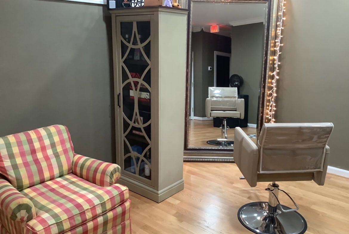 Modern salon styling chair in cozy hair salon with large mirror and decorative lighting.