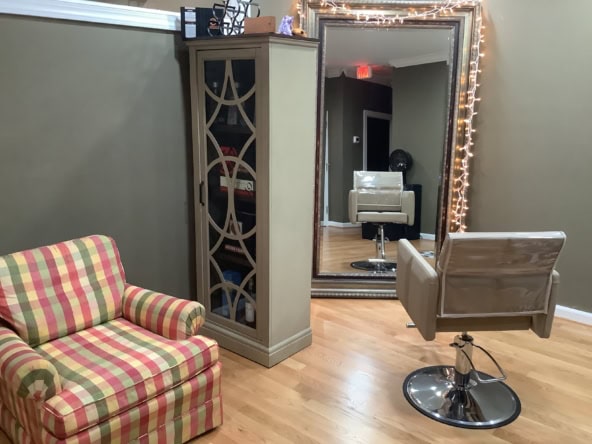 Modern salon styling chair in cozy hair salon with large mirror and decorative lighting.