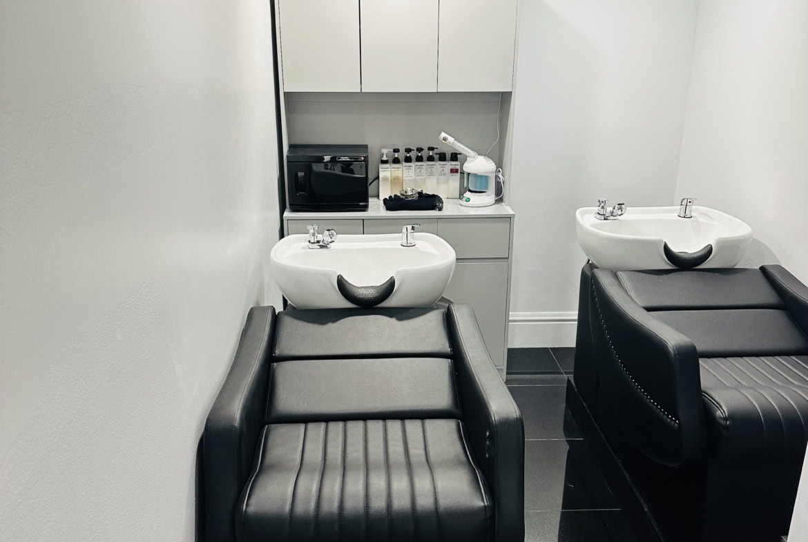Modern salon shampoo station with black reclining chairs and white sinks, perfect for hair treatments and styling.